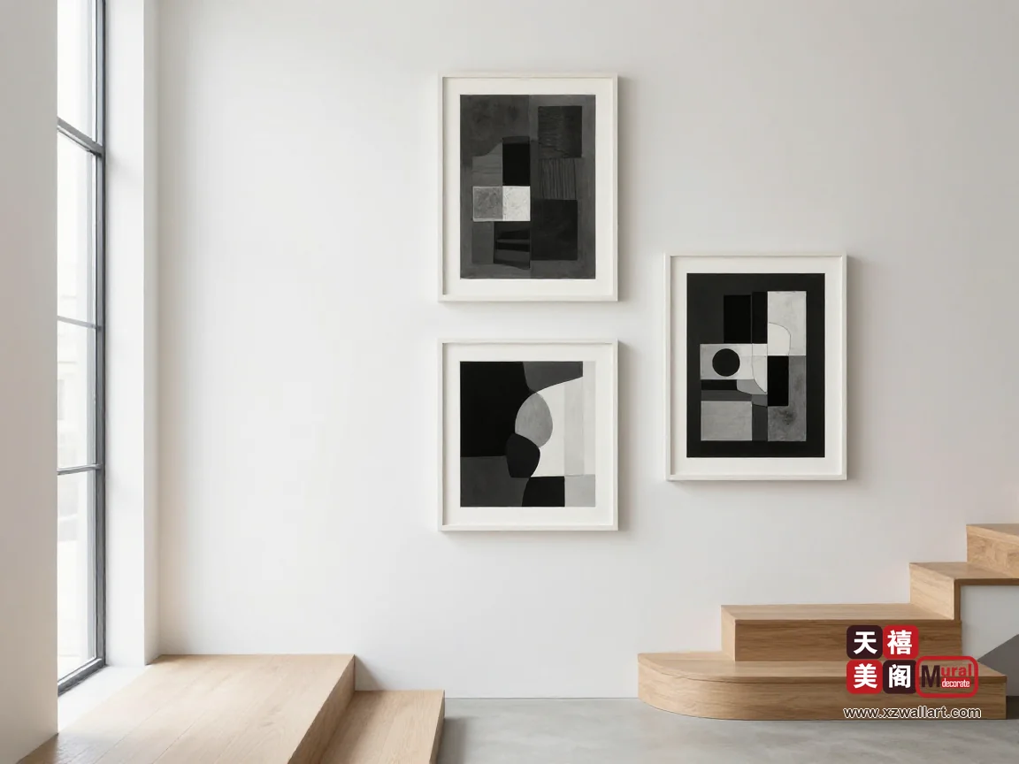 白色楼梯间里,浅橡木踏步沿墙向上,三幅黑白画自下而上逐幅放大,楼梯窗的自然光斜照在墙面上