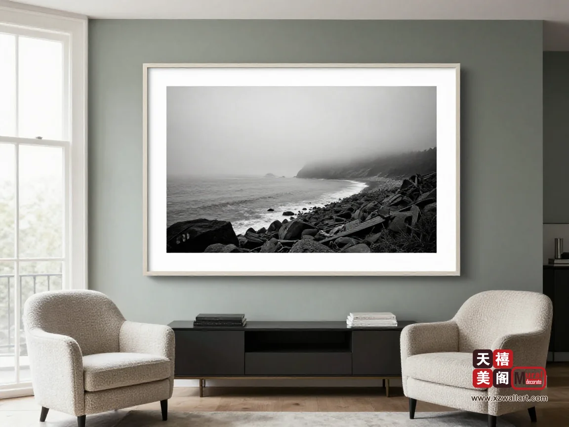 灰绿石灰墙客厅里,一幅黑白海岸雾景的横画挂在矮柜上方,北向天光均匀铺开